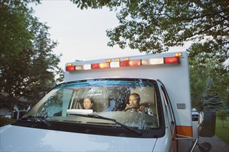 Male and female paramedics in cab of ambulance