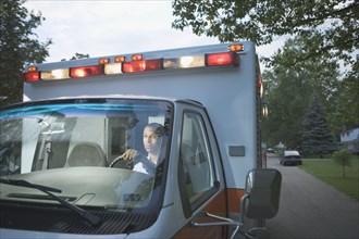 African male paramedic driving ambulance in residential area