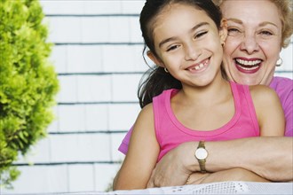 Hispanic grandmother and granddaughter hugging