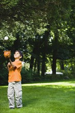 Hispanic boy playing with baseball in park