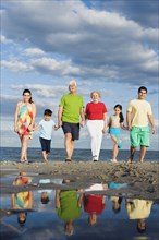 Hispanic family holding hands and walking on beach