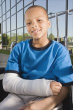 Close up of African boy with broken arm in wheelchair outdoors