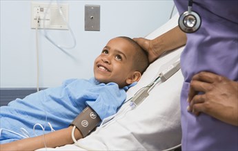 African boy smiling at nurse in hospital bed