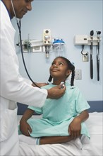 Young African girl being examined by doctor in hospital room