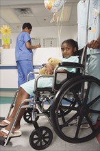 African girl being pushed in wheelchair in hospital
