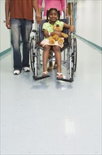 African girl smiling in wheelchair with parents in hospital