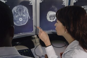 Hispanic female doctor pointing at brain scans