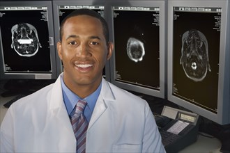 African male doctor smiling in front of brain scans