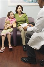 Doctor talking to Hispanic mother and daughter in waiting room