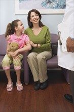 Hispanic mother and daughter talking to doctor in waiting room