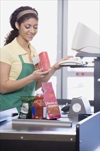 Mixed Race female grocery clerk ringing up items