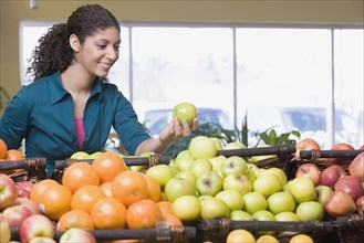 Mixed Race woman choosing apples at grocery store