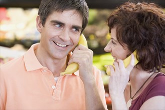 Couple playing with bananas at grocery store