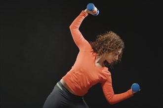 Mixed Race woman holding dumbbells