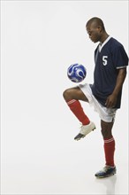 African American male soccer player bouncing ball