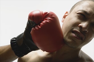 Mixed Race men getting punching with boxing glove