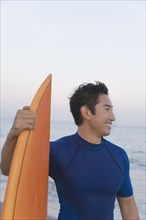 Asian man holding surfboard
