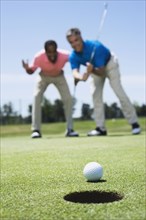 Multi-ethnic men looking at golf ball