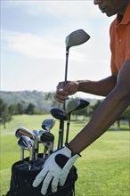 African man taking golf club from bag