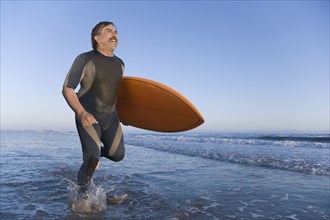Hispanic man carrying surfboard