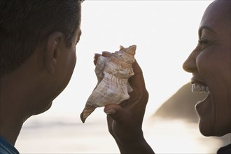 Mixed Race woman holding seashell next to husband