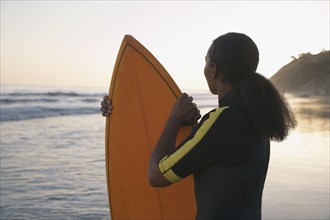 Mixed Race woman holding surfboard