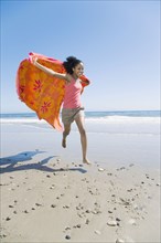 African woman running with beach towel