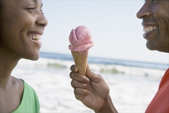 African couple sharing ice cream cone
