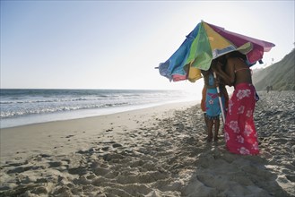 African family standing under beach umbrella