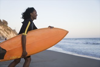 African woman carrying surfboard