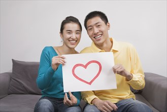 Chinese couple holding paper with heart