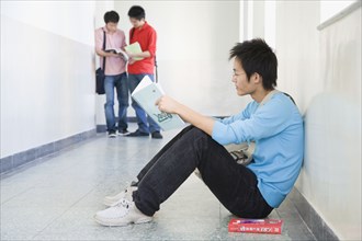 Chinese student reading notebook in corridor