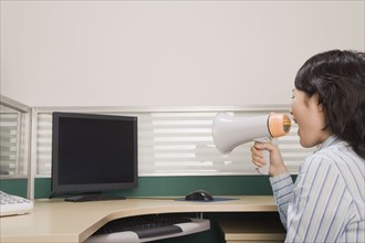 Chinese businesswoman yelling at computer through megaphone