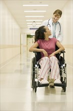 Doctor pushing patient in hospital hallway