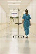 Nurse walking down hospital hallway with iv drip
