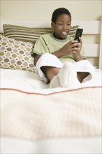 African American boy text messaging on cell phone