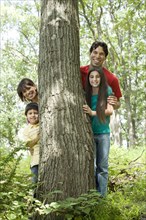 Family standing by tree trunk in forest