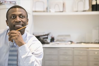 Black businessman daydreaming in office
