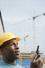 Black construction work in hard-hat using walkie-talkie