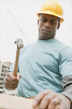 Black construction worker hammering wood