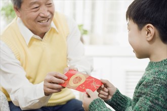 Chinese grandfather giving grandson envelope