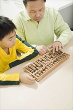 Chinese grandfather teaching abacus to grandson