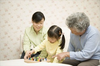 Chinese girl playing Chinese checkers with mother and grandmother