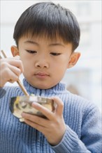 Chinese boy eating with chopsticks