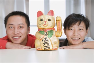 Chinese couple smiling next to cat figurine
