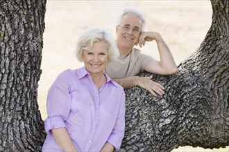 Caucasian couple leaning on tree