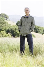 Caucasian man in field with hands in pockets