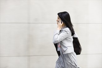 Chinese businesswoman walking and talking on cell phone