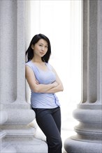 Chinese businesswoman leaning against stone pillar