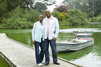 Smiling African American couple standing on pier at lake